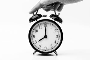 Person Touching Black Two-bell Alarm Clock