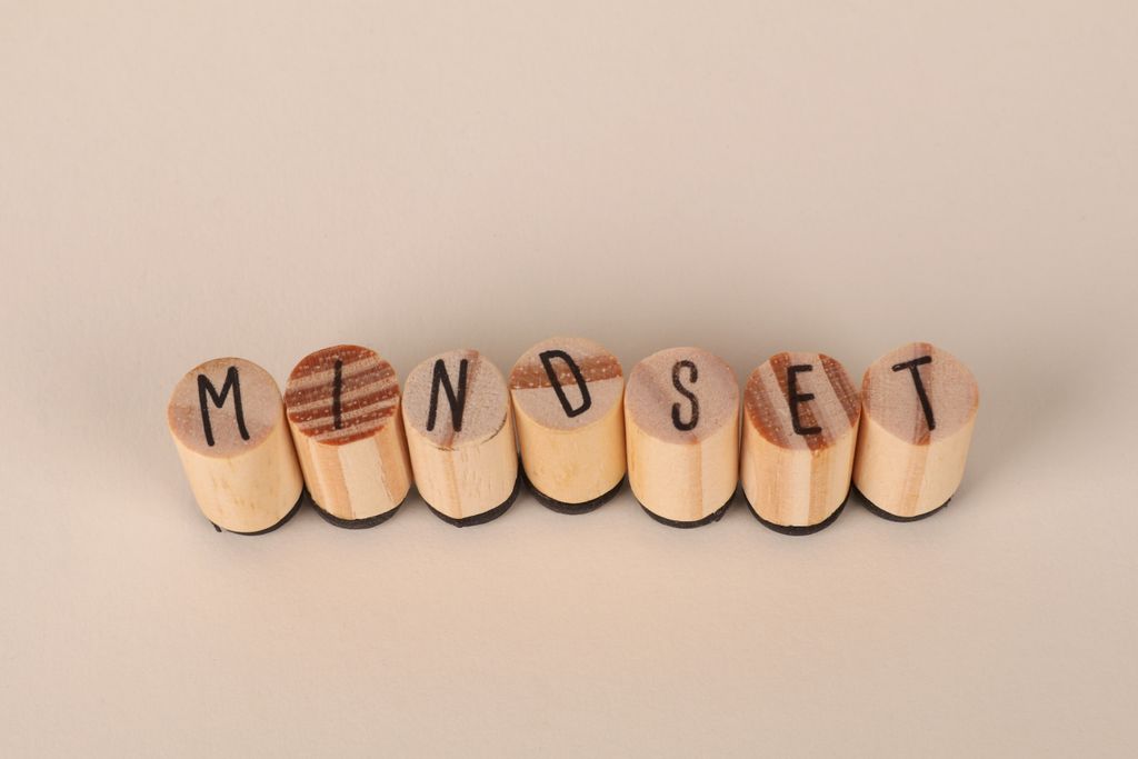 Wooden letter stamps spelling 'Mindset' on a simple beige background, conveying focus and positive thinking.